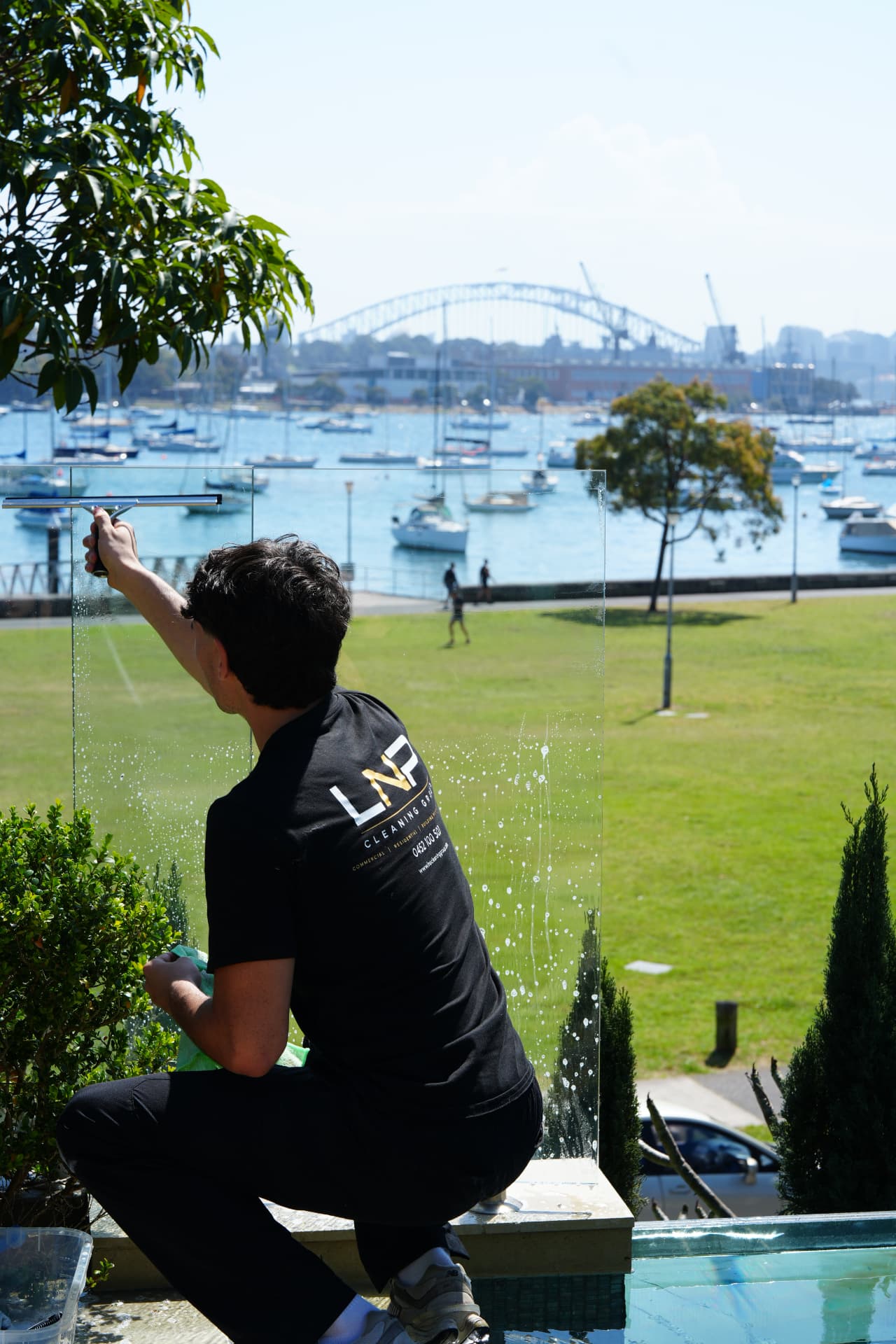 LNP team member cleaning glass balustrades overlooking Sydney Harbour