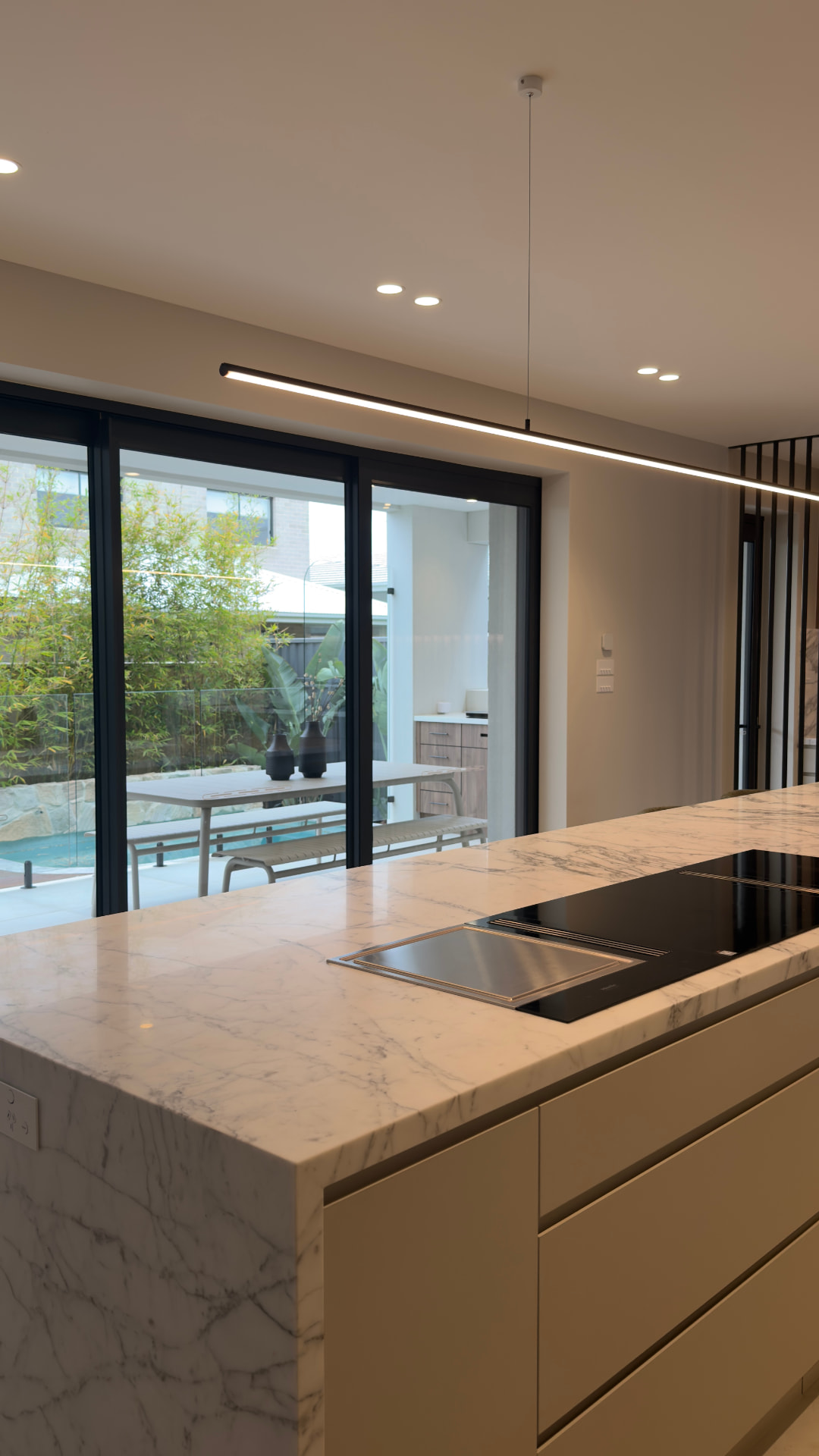 Marble kitchen island with sliding doors opening to a pool area